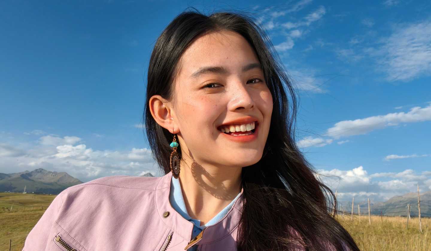 Radiant outdoor selfie of a smiling woman, captured by 50MP Luminous Selfie Camera