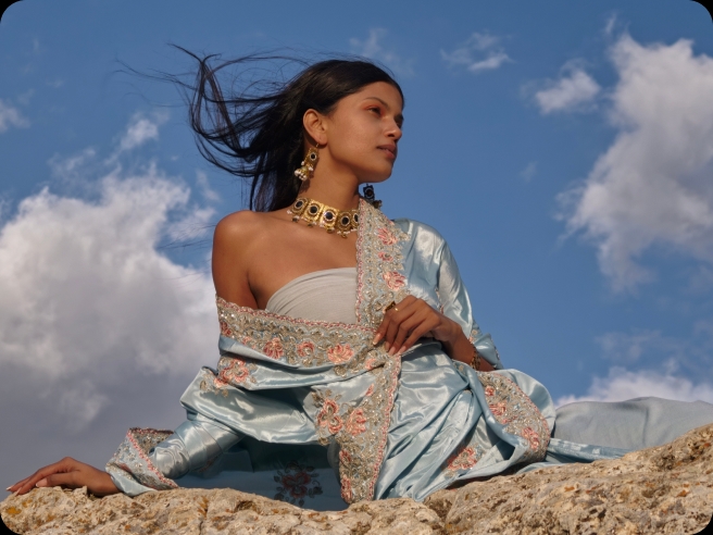 Woman in a blue embroidered dress against a bright sky, showing natural color from LUMO True Color Engine