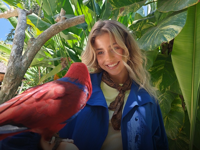 Detailed smartphone shot of a vibrant red parrot and a smiling woman, showcasing motion photography of OPPO Find X10
