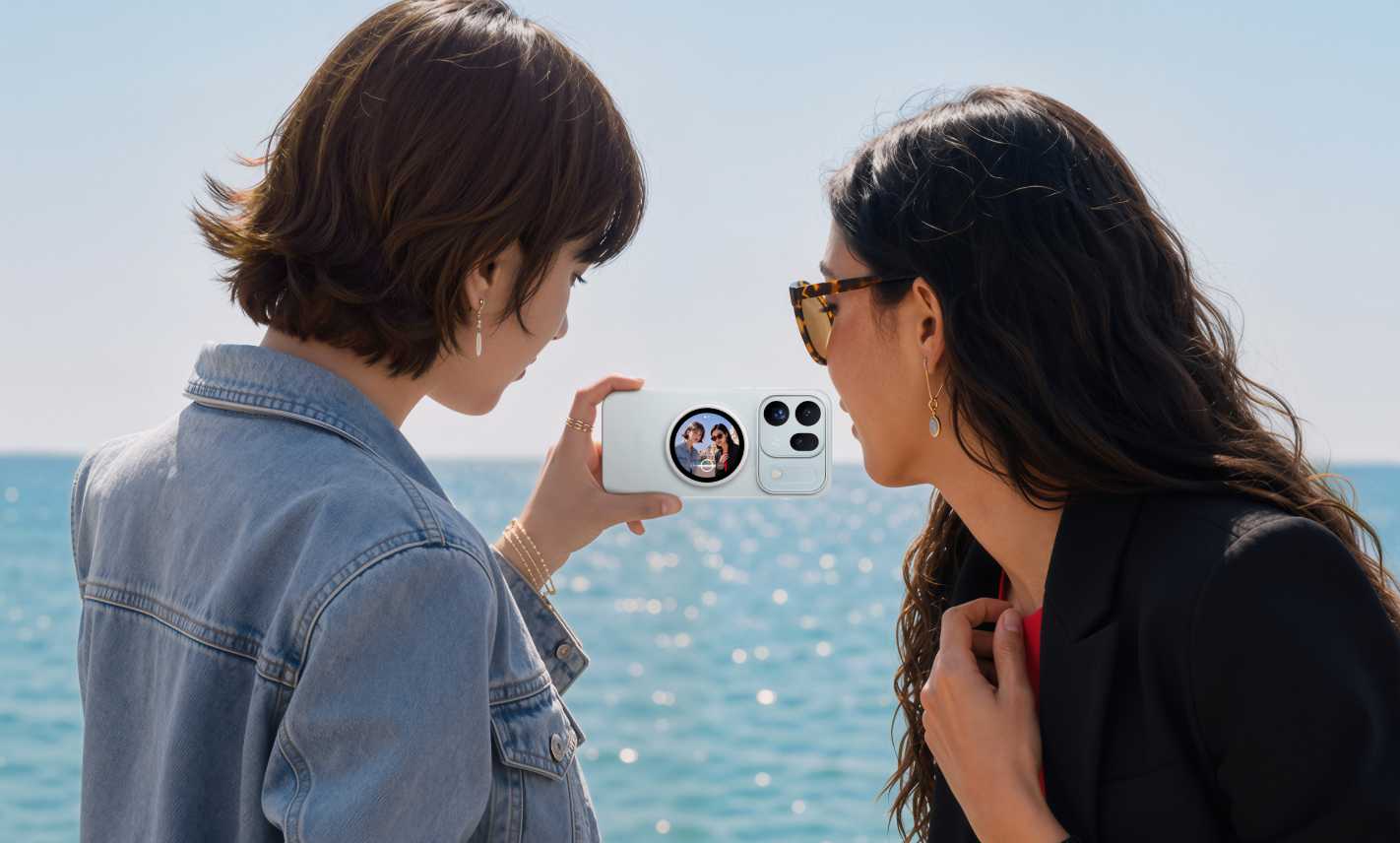 Dwie przyjaciółki kadrujące nadmorskie selfie przy użyciu tylnego wyświetlacza OPPO Bubble