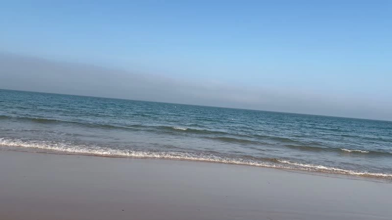 A video screenshot of a winking girl on a beach with a noticeably tilted horizon, demonstrating uncorrected handheld footage