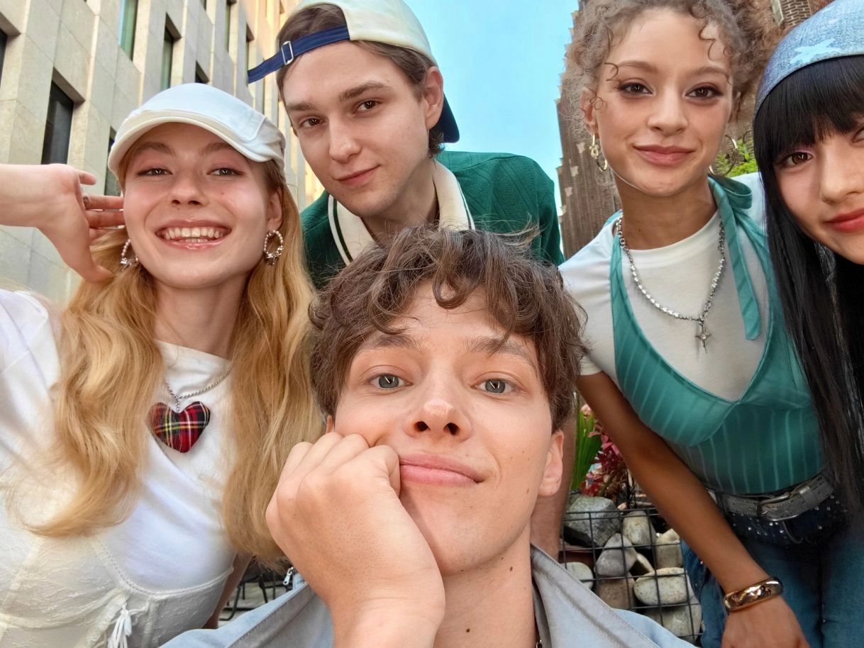1x selfie camera sample. Five friends take a lively group selfie in a city, capturing clear and natural facial details