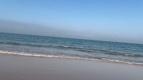 A video screenshot of a winking girl on a beach with a noticeably tilted horizon, demonstrating uncorrected handheld footage